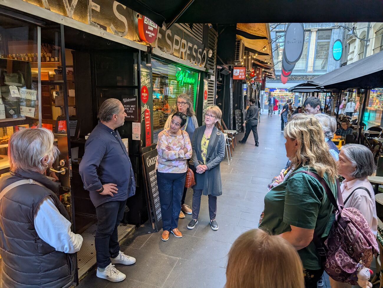 A Depot guide standing beside a Degraves Street trader while the trader talks to a tour group