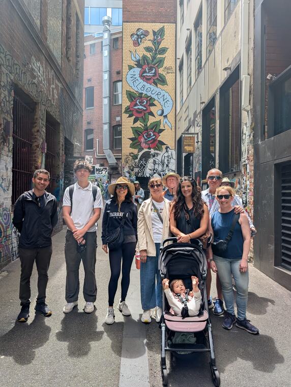 A family group with a pram in front of the Melbourne mural in Hosier Lane