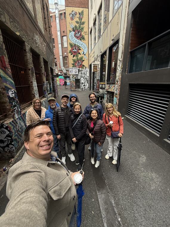 A guide taking a selfie with a tour group in Hosier Lane on a wet day