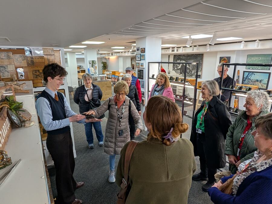 A guide showing a fossil to guests inside a small Melbourne museum